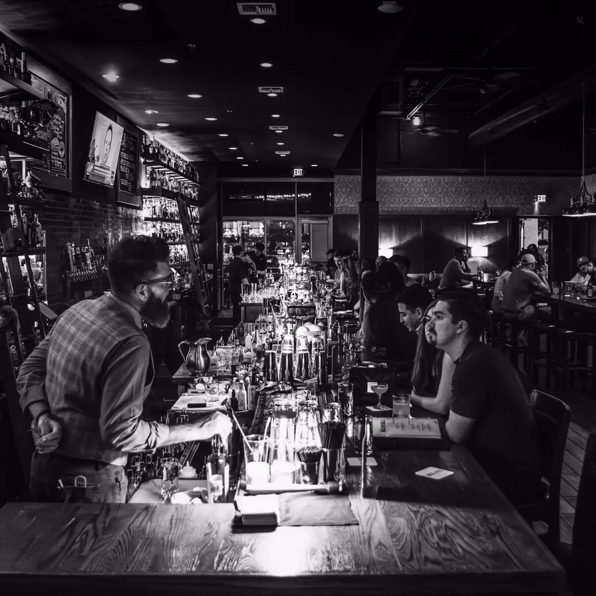 A full bar at Rock and Rye, bartenders at work, in black and white